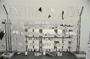 Muro de la vergüenza en la Exposición derechos refugiados 11 vidas en 11 maletas