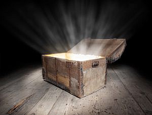 Ancient wooden treasure chest with the strong glow from inside.